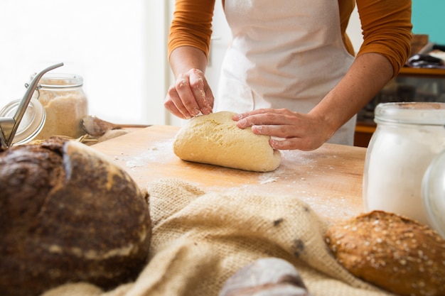 Free photo cook standing near table and forming dough on wooden board