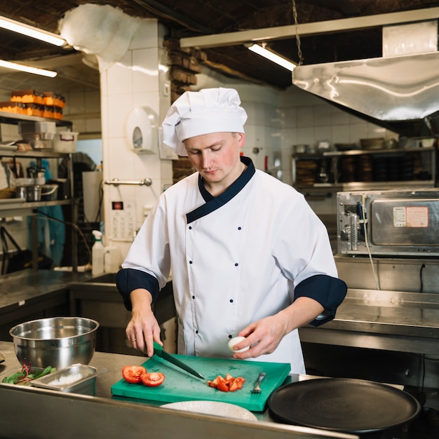 Free Photo cook standing with boiled egg and cut tomatoes 