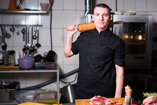 Free photo cook standing with rolling pin in hand