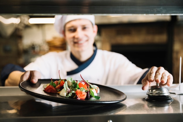 Free photo cook with salad ringing service bell