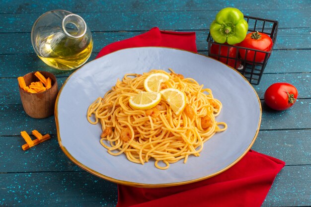 cooked italian pasta with lemon slices inside blue plate with oil and vegetables on blue