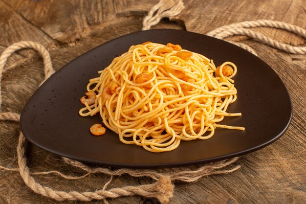 cooked italian pasta with shrimps inside brown plate with ropes on wooden desk