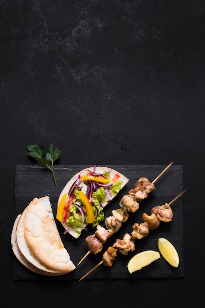 Free photo cooked meat and veggies kebab on black table