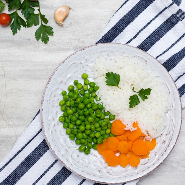 Cooked rice with vegetables and parsley on plate on striped napkin 