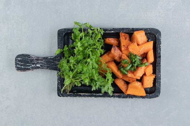 Free photo cooked sliced pumpkin next to parsley, on the tray , on the marble background.