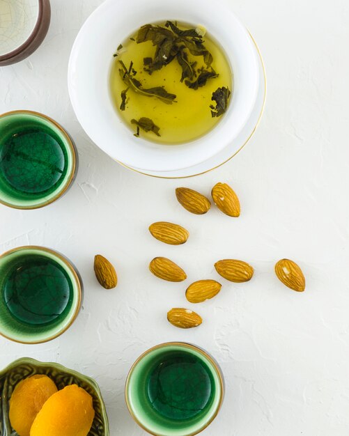 Cookies; almonds with herbal tea and cups on white textured background