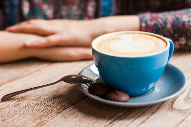 Free photo cookies and latte coffee cup in front of woman sitting in caf�