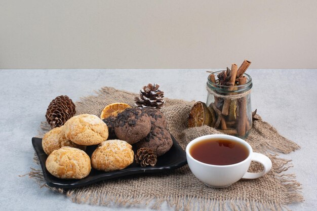 Cookies plate, tea, cinnamons and pinecones on burlap. High quality photo