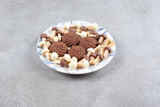 Cookies surrounded by chocolate mushrooms on a plate on marble background. High quality photo