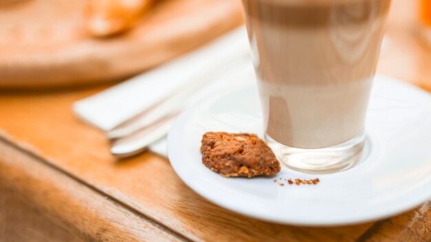 Cookies and transparent glass of coffee with cookie on saucer