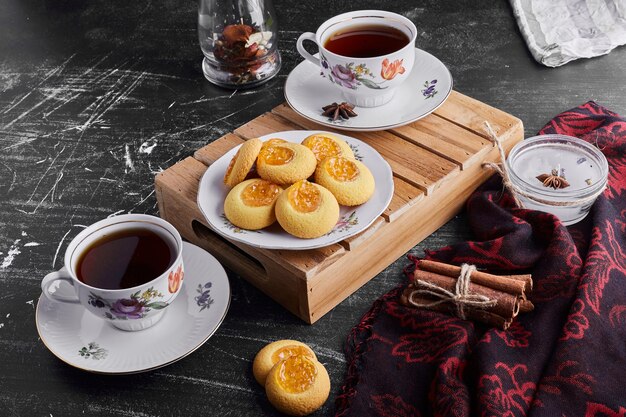 Cookies with apricot confiture with two cups of tea. 