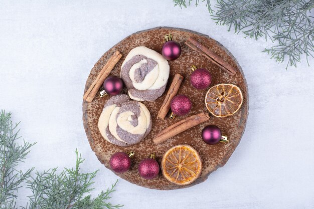 Cookies with baubles, cinnamons and orange slices on wood piece