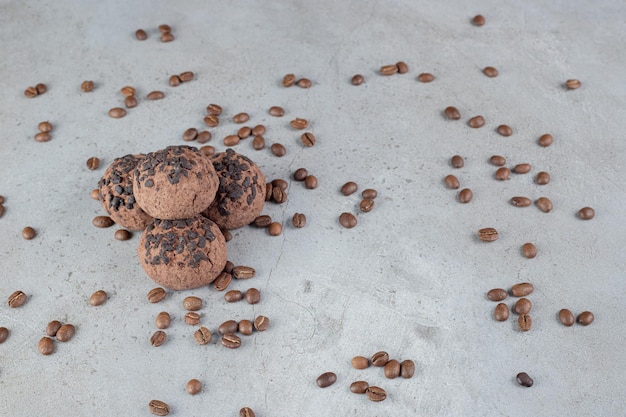 Free photo cookies with chocolate chip topping and scattered coffee beans on marble table.