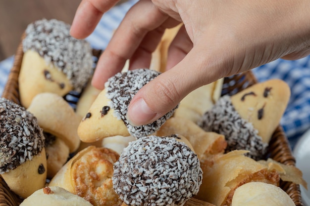 Cookies with chocolate and chopped coconut on wooden basket.