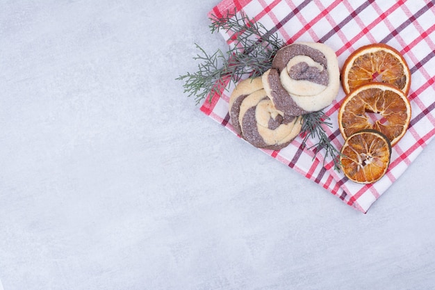 Cookies with dried orange on tablecloth and pine branch.