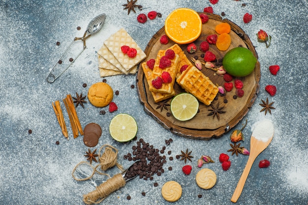 Free photo cookies with flour, herbs, fruits, spices, choco, strainer top view on wooden board and stucco background