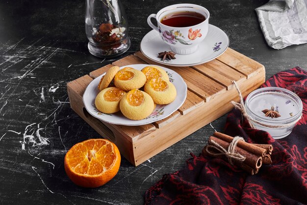 Cookies with orange jam served with a cup of tea. 