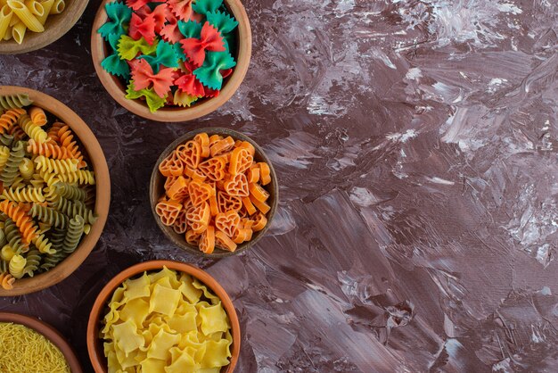 Free Photo cooking concept with variety of raw pasta on marble surface. 