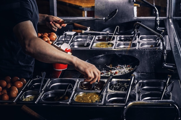 Free photo cooking process in an asian restaurant. cook is fry vegetables with spices and sauce in a wok