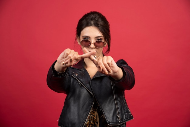 Cool girl in black leather jacket crossing hands or fingers to stop something. 