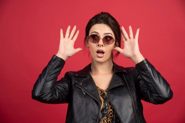 Cool girl in black leather jacket puts hands up and gives up. 