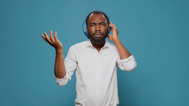 Cool happy man listening to stereo music on audio headset, using mp3 radio songs to have fun in studio. Funky cheerful person enjoying energetic sound on headphones, feeling joyful.