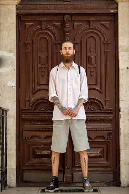 Cool hipster in white shirt posing in front of a door. Style and diversity