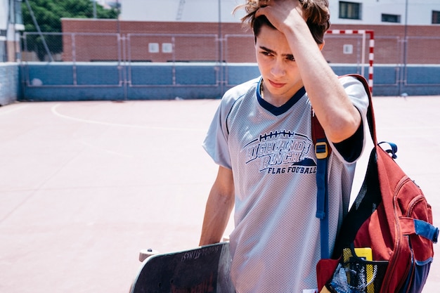 Free photo cool schoolboy with skateboard