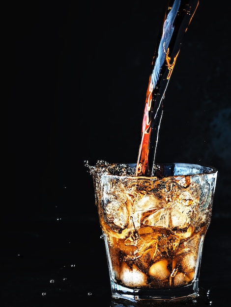 Free photo cool, soft carbonated cola drink is poured into a glass of ice