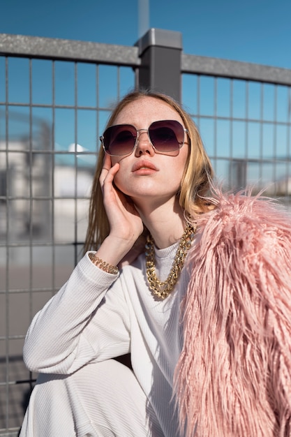 Free photo cool woman posing with sunglasses medium shot