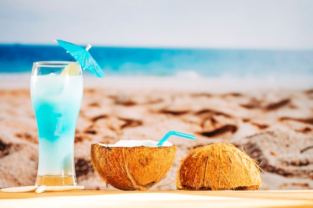 Free photo cooling blue cocktail and coconut milk on sandy beach