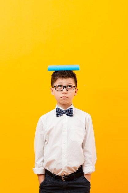 Free photo copy-space boy with book on head