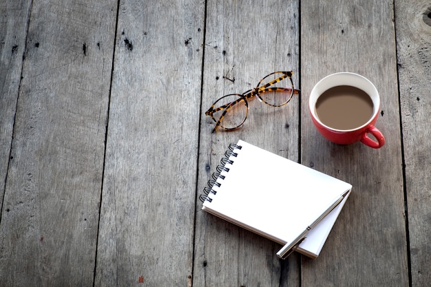 copy space of empty notebook and red cup of coffee on wooden background