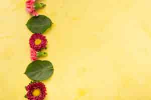 Free photo copy space yellow background with stripe of flowers and leaves