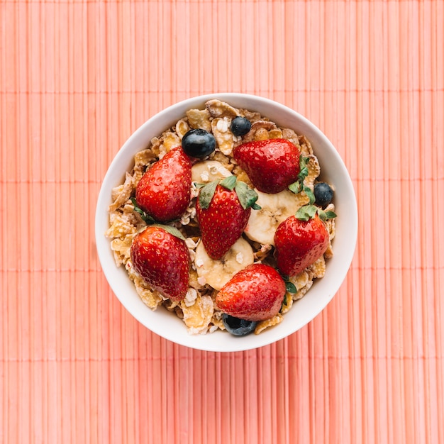 Free Photo corn flakes with berries on pink table