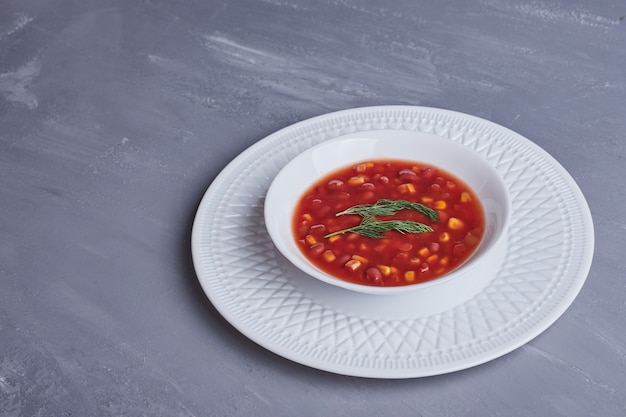 Corn soup in tomato sauce in a white plate.