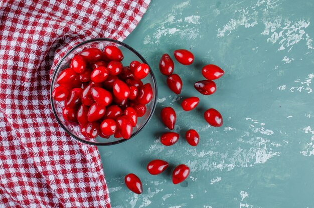 Cornel berries in a bowl on plaster and picnic cloth. flat lay.