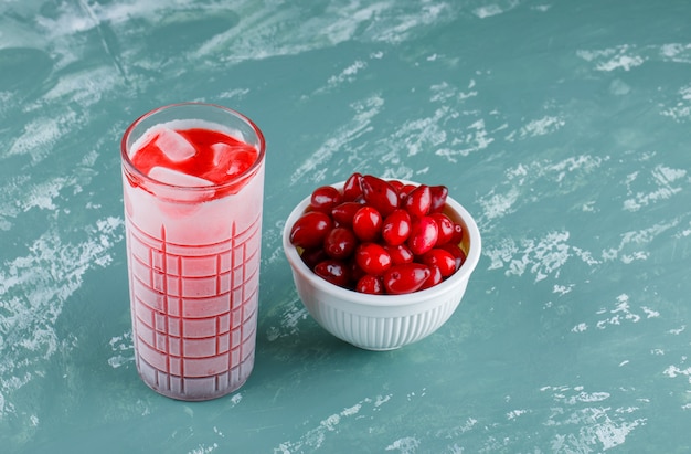 Free Photo cornel berries in a bowl with drink high angle view on plaster