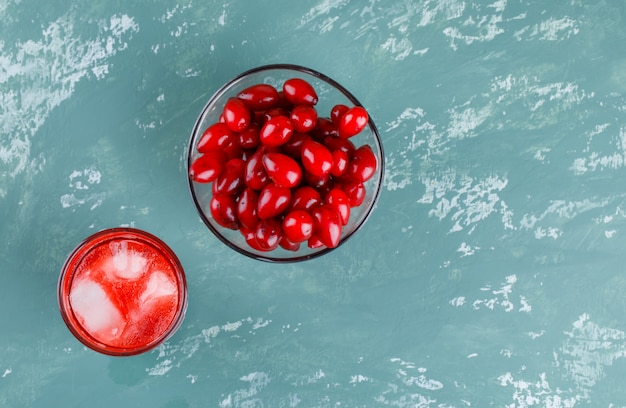 Free photo cornel berries in a bowl with drink on plaster