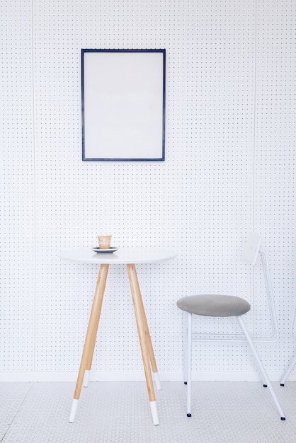 Free Photo corner of a kitchen with a table, gray chairs and a poster hanging on a light gray wall.