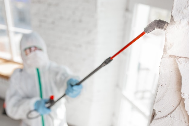 Coronavirus Pandemic. A disinfectant in a protective suit and mask sprays disinfectants in the room.