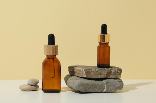 Cosmetic bottles and stones on light background