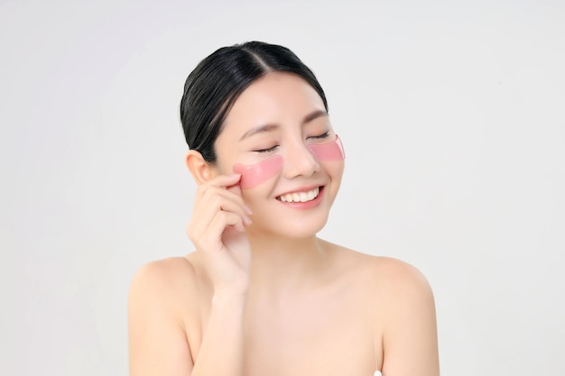 Cosmetic Eye Mask Close Up Beauty Face Asian Woman With Fresh Clean Skin Using Eye Pad Eye Care Treatment Isolated on white Beauty And Skin Care Concept