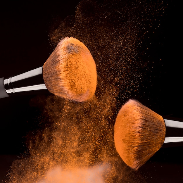 Free photo cosmetic tools and orange powder on black background