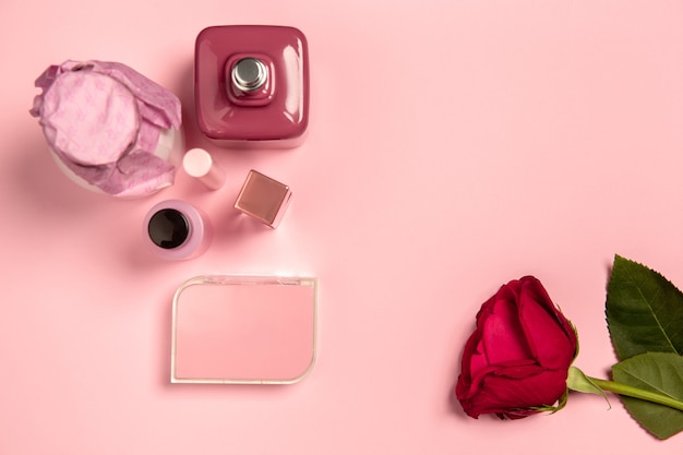 Free photo cosmetics, parfume and rose. monochrome stylish and trendy composition in pink color on studio wall. top view, flat lay.