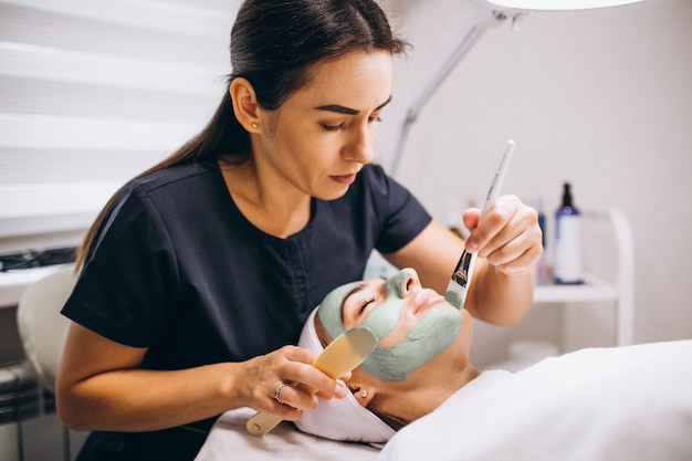 Free photo cosmetologist applying mask on a face of client in a beauty salon