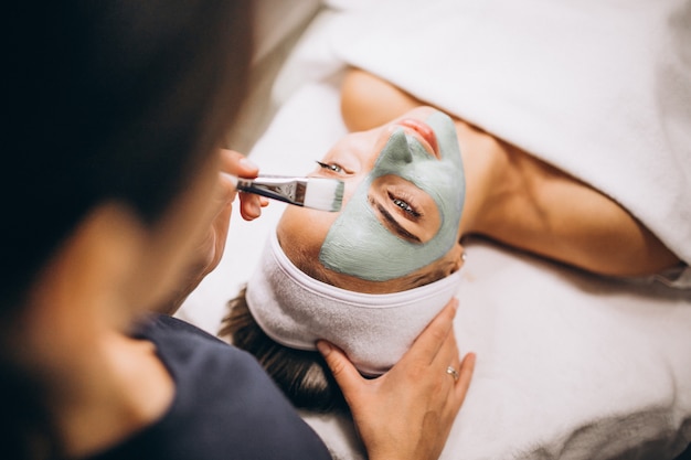 Free Photo cosmetologist applying mask on a face of client in a beauty salon