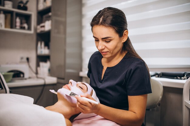 Cosmetologist applying mask on a face of client in a beauty salon