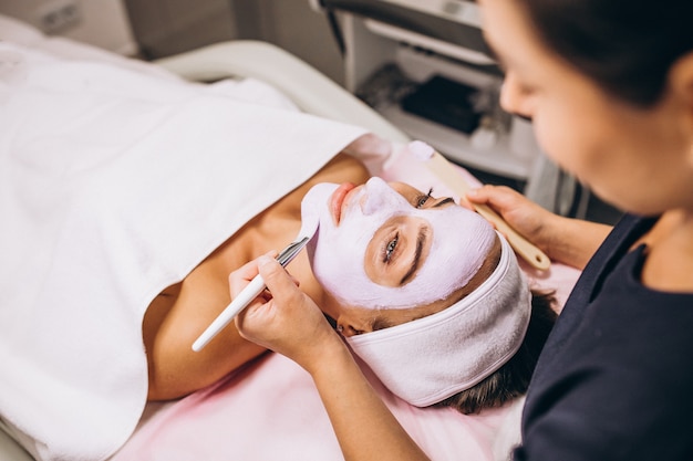 Free Photo cosmetologist applying mask on a face of client in a beauty salon