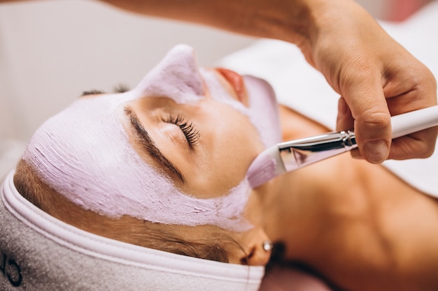 Cosmetologist applying mask on a face of client in a beauty salon